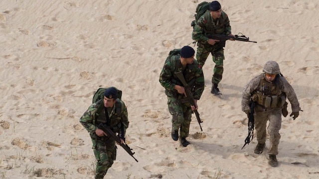 A U.S. Marine with the 26th Marine Expeditionary Unit, from the USS Arlington moves with Portuguese Marines at Pinheiro Da Cruz, Praia Da Raposa beach in Portugal, while participating in a combined amphibious assault exercise, Oct. 20, 2015, during Trident Juncture 15. Trident Juncture is a NATO-led exercise designed to certify NATO response forces and develop interoperability among participating NATO and partner nations. 