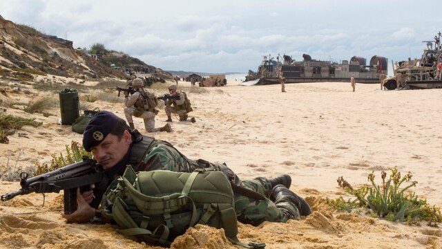 A Portuguese Marine holds security at Pinheiro Da Cruz, Praia Da Raposa beach in Portugal, while participating in a combined amphibious assault exercise, Oct. 20, 2015, during Trident Juncture 15. Trident Juncture is a NATO-led exercise designed to certify NATO response forces and develop interoperability among participating NATO and partner nations. 
