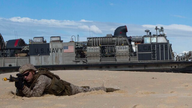 A U.S. Marine with the 26th Marine Expeditionary Unit, from the USS Arlington holds security with a Portuguese Marine at Pinheiro Da Cruz, Praia Da Raposa beach in Portugal, while participating in a combined amphibious assault exercise, Oct. 20, 2015, during Trident Juncture 15. Trident Juncture is a NATO-led exercise designed to certify NATO response forces and develop interoperability among participating NATO and partner nations. 