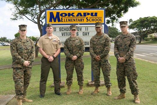 MARINE CORPS BASE HAWAII - Marines and sailors stand in front of Mokapu Elementary School’s sign aboard Marine Corps Base Hawaii, Nov. 5, 2015. These Marines and sailors rushed across the street to the scene where Robin Lopes, a sixth grade teacher at Mokapu Elementary School, was lying on the ground after she had a bicycle accident in the school parking lot. “I’ll always tell people from now on if they were to get hurt, pray there is a Marine Corps base around because literally a corpsman came and I was surrounded by Marines,” Lopes said. (U.S. Marine Corps photo by Lance Cpl. Zachary Orr)