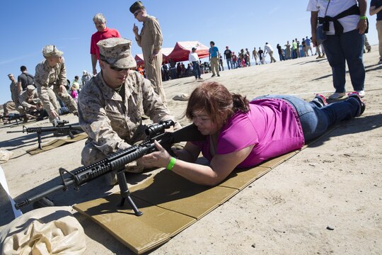 Lance Cpl. Nicholas Piedmonte, an airframe mechanic with Marine Light Helicopter Attack Training Squadron (HMLAT) 303, and an Austin, Texas, native, coaches Mirna Rivera, the mother of a Marine with HMLAT-303, and a San Salvador, El Salvador, native, while she holds an M-16 service rifle during the HMLAT-303 Family Day event aboard Marine Corps Base Camp Pendleton, Calif., Oct. 24. Marines and their family members visited one of Camp Pendleton’s ranges during family to experience firing a service rifle and watch an aerial demonstration. (U.S. Marine Corps photo by Sgt. Lillian Stephens/Released)