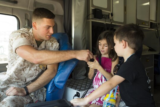 Lance Cpl. Thomas Kurtz, a member of the station special reaction team, shows Amelia and Jackson Morgan, event participants, how to use an intercom at Child Safety Day Event aboard Marine Corps Air Station Iwakuni, Japan, Aug. 27, 2015. Safety personnel shared safety tips with children and demonstrated emergency procedures. (U.S. Marine Corps photo by Lance Cpl. Nicole Zurbrugg/Released)