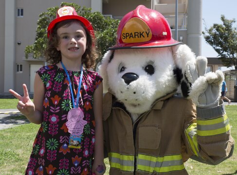 Ava Keller, an event participant, poses with Sparky the Fire Dog at Child Safety Day Event aboard Marine Corps Air Station Iwakuni, Japan, Aug. 27, 2015. The event taught kids a variety of safety tips from how to properly hold a baby and the correct way to wear a back pack, to bicycle safety and household hazards. (U.S. Marine Corps photo by Lance Cpl. Nicole Zurbrugg/Released)