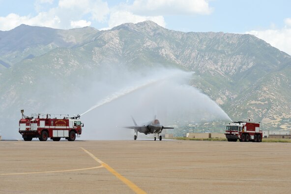 An F-35A Lightning II aircraft passes under a water arch at Hill Air Force Base, Utah, Sept. 2, 2015. The jet and another F-35A, the first of the Air Force’s newest fifth-generation fighter aircraft to arrive at the base, were delivered by Col. David Lyons, 388th Fighter Wing commander, and Lt. Col. Yosef Morris, 34th Fighter Squadron director of operations. The rest of the fleet of up to 72 F-35s will be coming in on a staggered basis through 2019. The 388th and 419th Fighter Wings at Hill were selected as the first Air Force units to fly combat-coded F-35s. (U.S. Air Force photo/R. Nial Bradshaw)