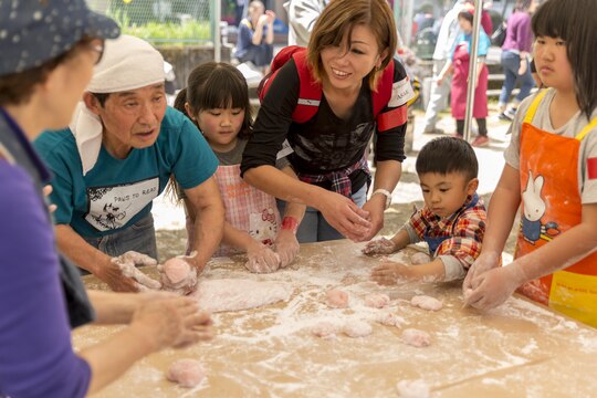 Japanese civilains roll mochi into balls during a Mochitsuki – rice pounding – event with residents from Marine Corps Air Station Iwakuni at Tenno Elementary School in Tenno, Japan, April 16, 2016. Commonly eaten during the Japanese New Year and festivals, mochi is made when glutinous rice is soaked, steamed and pounded with a wooden mallet and mortar, forming a sticky, stretchy texture. The rice is then rolled in flour and molded into round shapes to form mochi or rice cakes, which participants enjoyed in Japanese miso-based vegetable soup. (U.S. Marine Corps photo by Lance Cpl. Aaron Henson/Released)