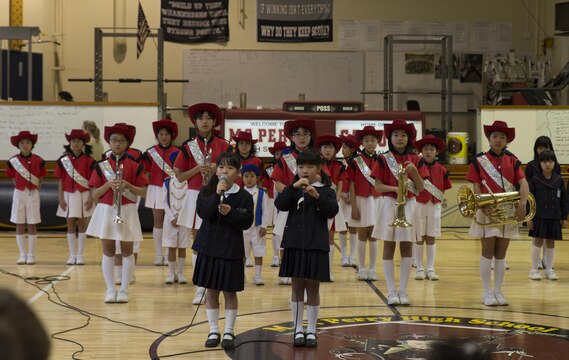 Eight-year-old Chinatsu Moriwaki and Sae Matsumoto, students of Fukugawa Elementary School, sing the “Star Spangled Banner” during a cultural exchange at Matthew C. Perry Elementary School Feb. 11, 2016. Fukugawa Elementary School is a member of the Shunan International Children’s Club that visits M.C. Perry Elementary School annually. Approximately 90 children’s club students, staff and government officials attended the cultural exchange.