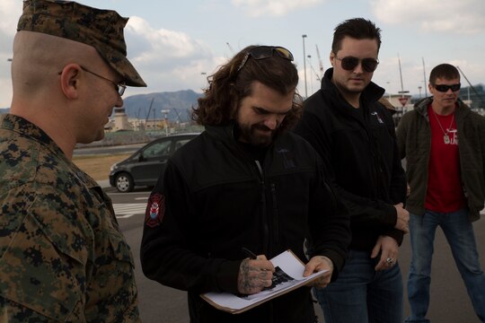 Chris Henderson, lead and rhythm guitarist of 3 Doors Downs, signs autographs for a Marine of Marine Aviation Logistics Squadron 12 during their visit to Marine Corps Air Station Iwakuni, Japan, Jan. 14, 2016. Members of the band said they do these tours in order to give back to the men and women who have already given so much.
