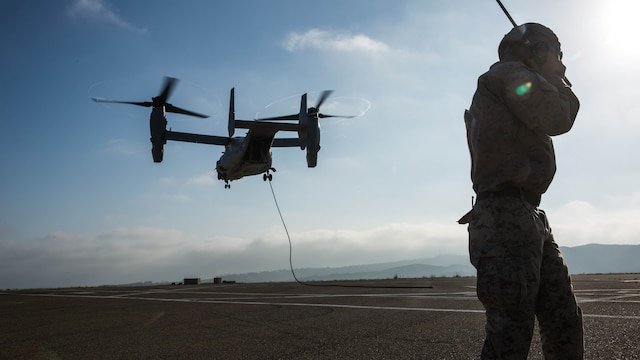 A Marine with 2nd Battalion, 5th Marine Regiment, Weapons Company, Scout Sniper Platoon, communicates with the pilots of an MV-22B Osprey with Marine Medium Tiltrotor Squadron 164 during fast-rope training aboard Marine Corps Base Camp Pendleton, Calif., June 30. The ability to fast rope enables Marines to insert into an area or structure without landing the aircraft, eliminating the need for a landing zone. 
