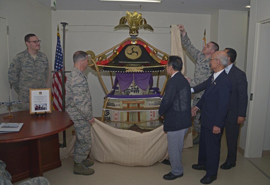 Members of the 374th Maintenance Group and Fussa-Yokota Goodwill Exchange Club unveil the mikoshi shrine during the rededication ceremony at Yokota Air Base, Japan, June 15, 2016. (U.S. Air Force photo by Senior Airman David Owsianka/Released)