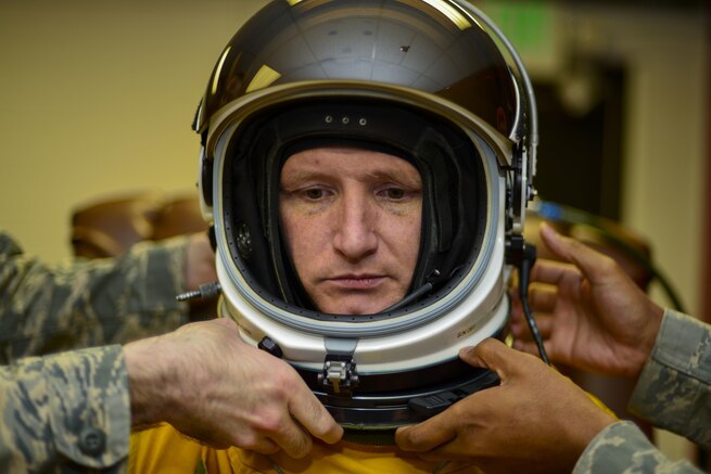 Air Force Lt. Col. Todd Larsen waits as airmen fasten his helmet to prepare him for a flight on a U-2 Dragon Lady at Osan Air Base, South Korea, June 16, 2016. All U-2 pilots wear pressurized suits to compensate for lack of atmosphere at the great heights they fly. Air Force photo by Senior Airman Victor J. Caputo