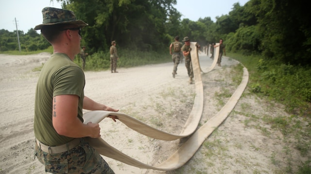 A Marine with Bulk Fuel Company, 8th Engineer Support Battalion, drags a hose meant to hook up to an amphibious assault fuel system at Marine Corps Base Camp Lejeune, North Carolina, June 24, 2016. A completed AAFS can hold approximately 1.12 million gallons of fuel, which is capable of supporting an entire Marine Expeditionary Force. 