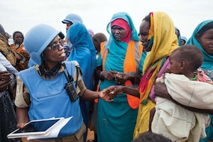 Community policing volunteers bridge divides in Darfur. In the Zam Zam camp for Internally Displaced People in North Darfur, UNAMID police officer Grace Ngassa, from Tanzania (left), and Community Policing Volunteer Jazira Ahmad Mohammad (center) interact with a woman and her child (right).
