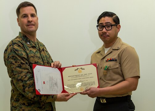 Petty Officer 3rd Class Jason Aguirre, right, a logistics specialist with Headquarters and Headquarters Squadron, poses for a photo with Col. Robert V. Boucher, commanding officer of Marine Corps Air Station Iwakuni, after being awarded the Marine Corps Installations Pacific Junior Sailor of the Year at MCAS Iwakuni, Japan, March 10, 2016. Aguirre said becoming sailor of the year wasn’t an easy task and participating in Marine Corps activities helped him achieve his newly appointed title. (U.S. Marine Corps photo by Lance Cpl. Aaron Henson/Released)