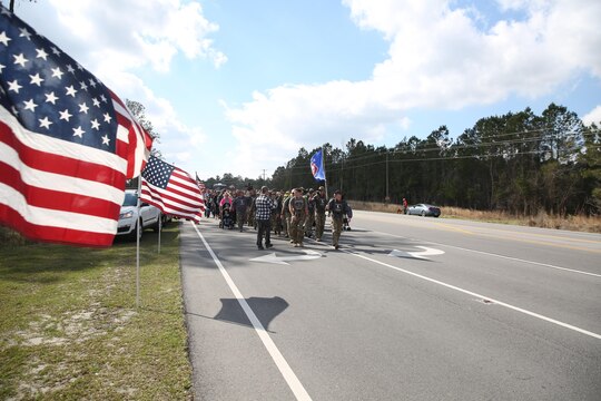 The local community lined the streets and cheered on the ruckers as they finished the Marine Raider Memorial March outside the Stone Bay main gate, aboard Marine Corps Base Camp Lejeune, N.C., March 21, 2016.  The Marine Raider Memorial March was designed to honor the seven Marine Raiders who died on March 10th, 2015 and their families, as well as bring awareness to their sacrifice. The ruckers were made up of both active duty and former Raiders, family members, and close friends. Following the conclusion of the March there was a short ceremony to honor the fallen. 