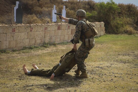 MARINE CORPS BASE HAWAII—  Cpl. Bradley Saunders, an infantry assaultman with Fox Company, 2nd Battalion, 3rd Marine Regiment, and a Platteville, Wis., native, drags a training dummy while shooting targets with his M9 Service Pistol during a Pacific Combat Shooting Match at the Kaneohe Bay Range Training Facility aboard Marine Corps Base Hawaii, March 16, 2016. Teams from different units used various weapons and tactics to achieve the fastest time possible on different courses of fire, while earning points for awards during the competition. Marines from the Marine Corps Combat Shooting Team instructed and gave advice to the Marines participating in the event. (U.S. Marine Corps Photo by Lance Cpl. Jesus Sepulveda Torres)
