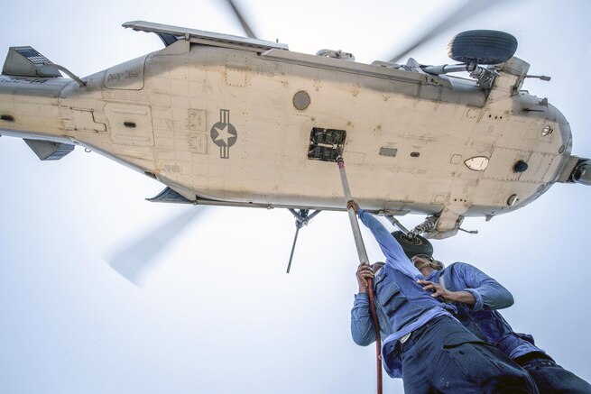 Navy Seaman Apprentice Deandre Robertson and Seaman Alonzo Brantley hook a pendant cargo line to an MH-60S Seahawk helicopter during a vertical replenishment on the USS Mobile Bay in the South China Sea, May 6, 2016. The Bay is operating on a regularly scheduled 7th Fleet deployment. Navy photo by Petty Officer 2nd Class Ryan J. Batchelder