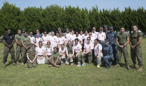 Headquarters and Headquarters Squadron spouses, Marines and sailors pose together after the 2016 Spouse Family Day, also known as Jayne Wayne Day, at Marine Corps Air Station Iwakuni, Japan, May 14, 2016. Designed to build unit and family cohesion, this event gives insight as to what military sponsors experience daily and showcases how Marines operate and train here. Participants learned about various aspects of the Marine Corps lifestyle from strict hair regulations, fitness standards and military bearing, to how Marines operate weapons, utilize specific equipment for their jobs and different professions within the organization. (U.S. Marine Corps photo by Cpl. Justin Fisher/Released)