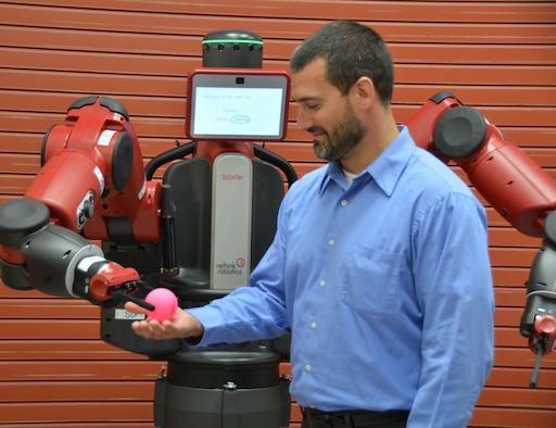 Dr. Joseph Lyons, Human Trust and Interaction Branch technical advisor, is given a ball by the Baxter robot after instructions were given to the robot by a member of Lyons' team. (U.S. Air Force photo / Gina Marie Giardina)