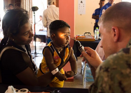 Lt. Cmdr. Scott Williams examines a child's eyes during Pacific Partnership 2018.