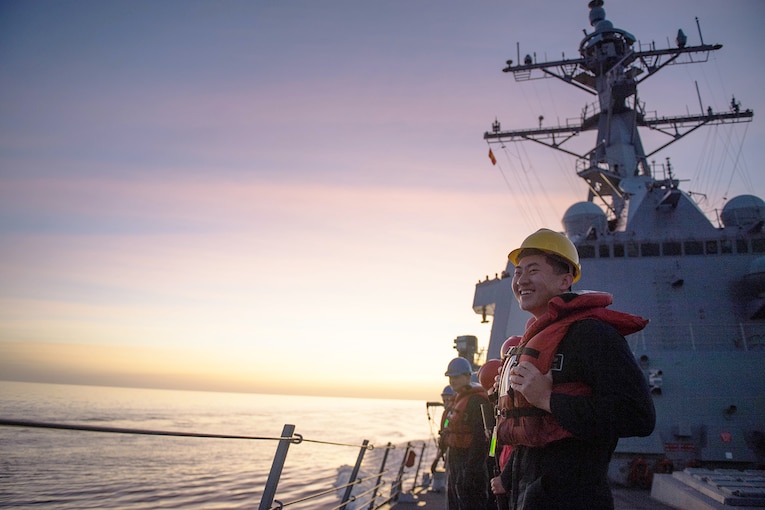 A service member stands aboard a ship.
