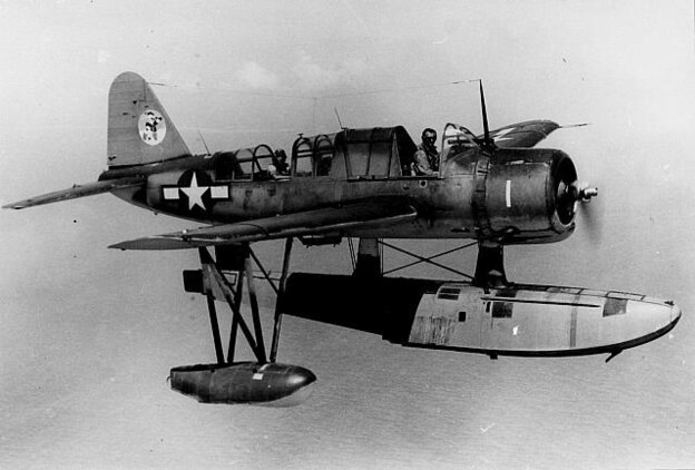 An OS2N-1 ?Kingfisher? observation/scout float plane in flight, the same model as the Kingfisher that Radioman 2nd Class Harrison D. Miller successfully made an emergency water landing with no prior flying experience, no flight instruments and only an emergency control stick in the rear cockpit.