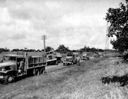 A Red Ball Express convoy of U.S. military trucks stops to help a disabled truck on a road in France in 1944 during World War II.