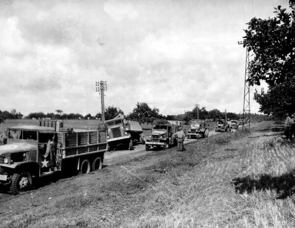 A Red Ball Express convoy of U.S. military trucks stops to help a disabled truck on a road in France in 1944 during World War II.