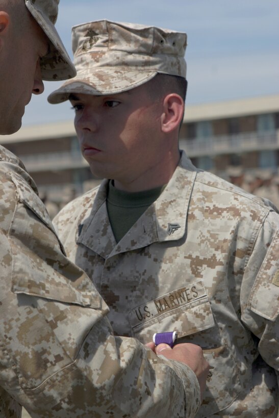 MARINE CORPS BASE CAMP LEJEUNE, N.C.?Lt. Col. Todd Desgrosseilliers, commanding officer of 3rd Battalion, 2nd Marine Regiment, 2nd Marine Division, presents the Purple Heart medal to Cpl. Christopher Grubb during a ceremony in front of the battalion, April 6.  Grubb received the medal for wounds sustained on Sept. 1, 2006.  That night Grubb, a squad leader with 3rd Bn., 2nd Marines, led his squad on a combat patrol.  One of Grubb?s fire team leaders, Lance Cpl. Cliff Golla, stepped on a pressure-plate, setting off an improvised explosive device.  The blast killed Golla and severely injured three other Marines, including Grubb.