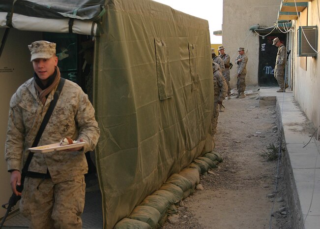 A Marine from the 22nd Marine Expeditionary Unit (Special Operations Capable) emerges from the serving line of Field Food Service System located aboard Forward Operating Base Hit, Iraq, Dec. 23, 2005.  The mobile kitchen belongs to the 2nd Marine Logistics Group, and is currently being operated in support of the 22nd MEU (SOC) as the unit conducts counterinsurgency operations in Iraq's Al Anbar province.