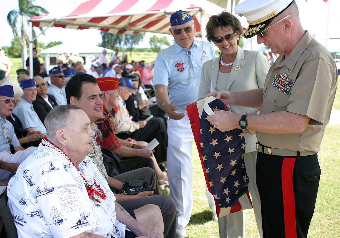 Brig. Gen. George J. Trautman III (right), commanding general of MCB Hawaii, and his wife, Zoe, take a look at an authentic United States flag taken from Iwo Jima by Leo B. Rodby Jr. (front-left), after the battle.  Rodby, accompanied by his son, Peter, kept the flag that came from his landing craft (LCT 1404) over the past 60 years as a momento.  Approaching from the rear to assist in unfurling the flag is James Ward, vice president of The Chosin Few, Aloha Chapter.