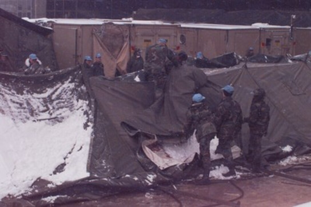 The hospital red cross is removed by members of the 74th Medical Group (Provisional) after the dropping of one of the tents on Dec. 6, 1995, as part of the closing of the U.S. Hospital Zagreb at Camp Pleso, Zagreb, Croatia. The tents of the hospital are being emptied of medical equipment and supplies and taken down by the 74th Medical Group (Provisional), of Wright-Patterson Air Force Base, Ohio. The hospital has served the United Nations Protection Force since November of 1992. 