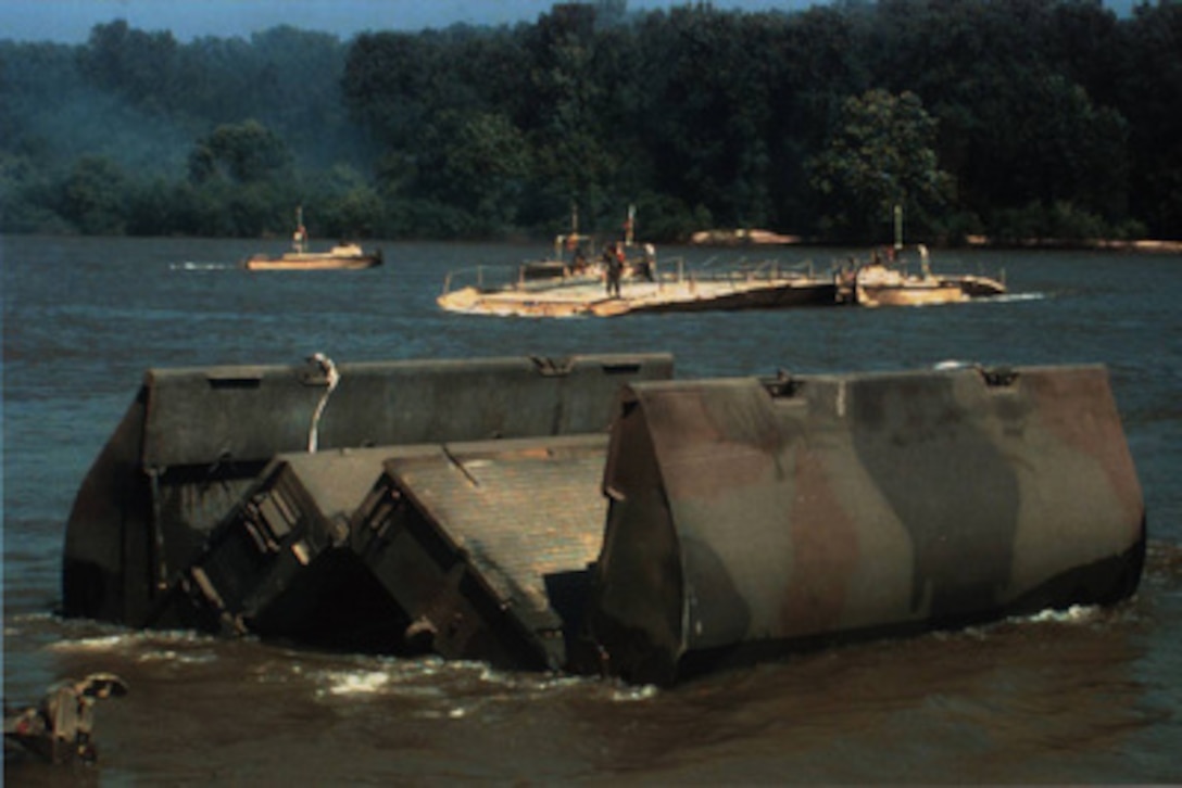A section of a ribbon float bridge known as a bay unfolds as it is deployed into the Arkansas River during field training near Fort Chaffee, Ark., in July. Ribbon bridges like this will be used by the Army's 1st Armored Division to cross the Sava River between Croatia and Bosnia and Herzegovina. The engineers are part of the NATO Enabling Force of Operation Joint Endeavor. Enabling forces are moving into the Croatia, Bosnia and Herzegovina, and Slovenia theaters of operation to prepare entry points for the main Implementation Force. 