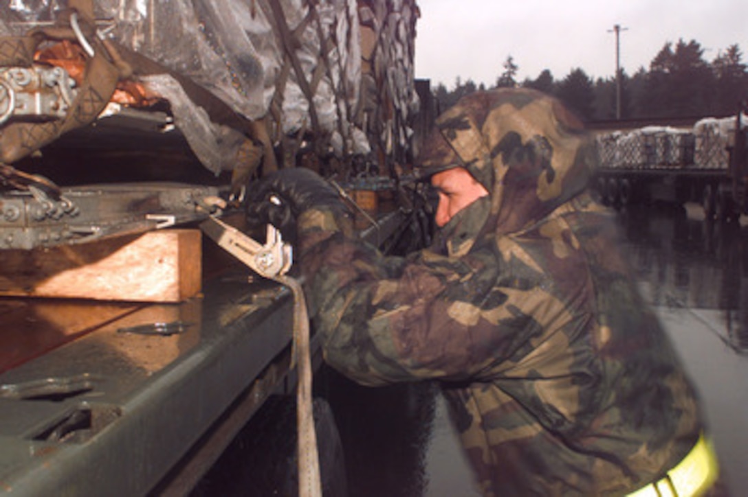 U.S. Air Force Senior Airman John Gonzales tightens a strap around a pallet of equipment, securing it to a flatbed truck at Ramstein Air Base, Germany, on Dec. 21, 1995. Gonzales will deliver the equipment to a marshaling yard where it will be given a chalk number and await transportation. Equipment from all over the world is arriving at Ramstein to be staged for deployment to Bosnia and Herzegovina where it will be used by the NATO Implementation Force (IFOR). Gonzales is attached to the 86th Transportation Squadron at Ramstein. 