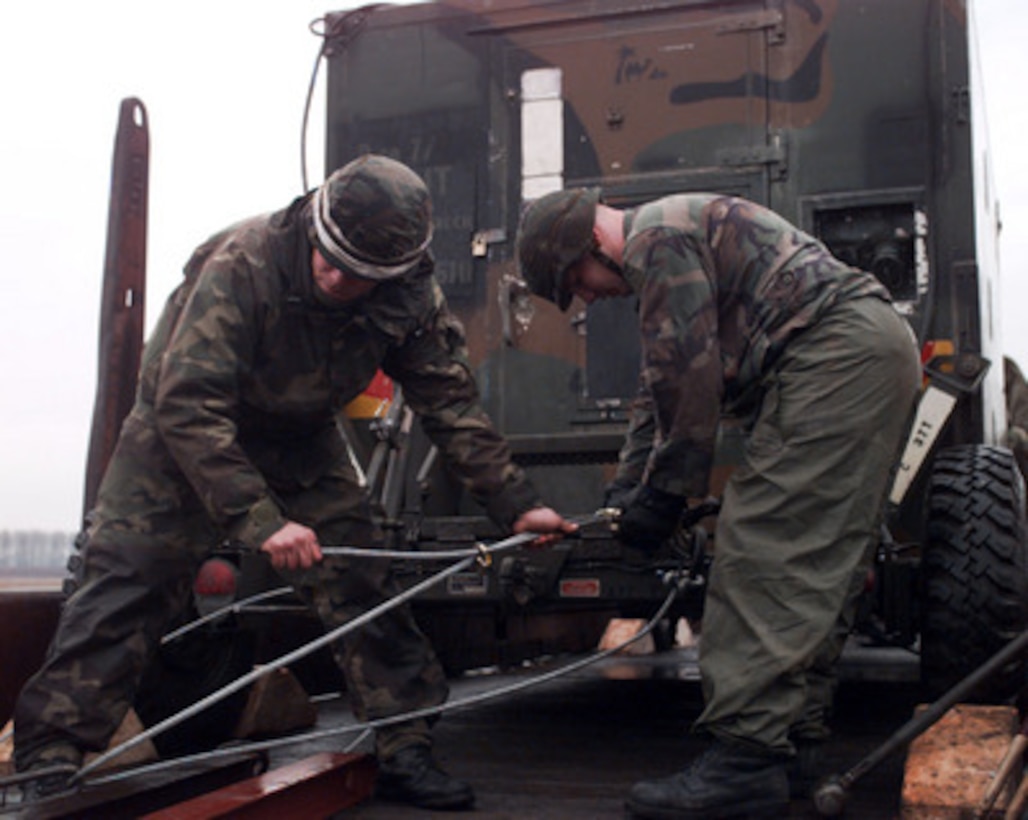 U.S. Army Spc. Daniel Wies (left) and Pfc. Leonard Lucas (right) secure a vehicle to a railroad car at Hanau, Germany, on Dec. 22, 1995, for deployment to NATO's Operation Joint Endeavor. Military equipment from all over the world is being deployed to Bosnia and Herzegovina where it will be used by the NATO Implementation Force (IFOR). Wies is attached to Bravo Company, 578th Air Defense Artillery Battalion. Lucas is attached to the Delta Company 7, 277th Aviation Battalion, Hanau, Germany. 