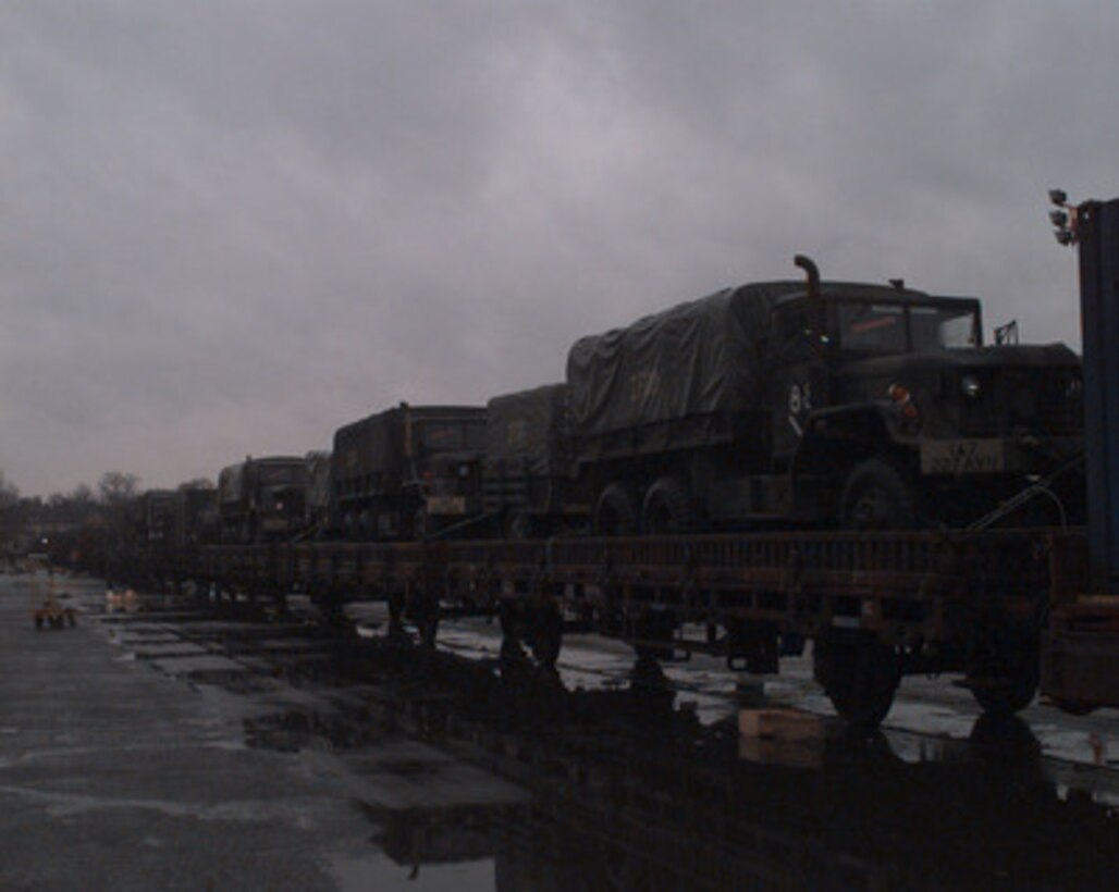 U.S. Army 5-ton trucks are secured to a railroad car at Hanau, Germany, on Dec. 22, 1995, for deployment to NATO's Operation Joint Endeavor. Military equipment from all over the world is being deployed to Bosnia and Herzegovina where it will be used by the NATO Implementation Force (IFOR). 