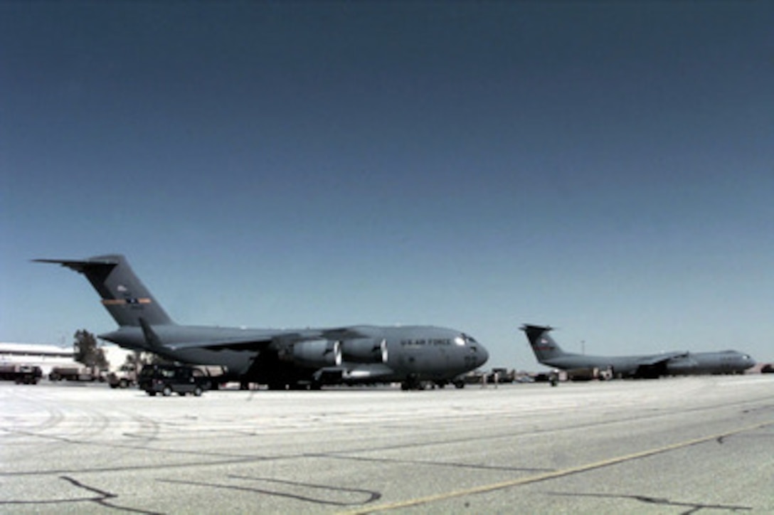 U.S. Air Force personnel from the 621st Aerial Port Squadron unload a C-17 Globemaster III (left) and a C-141B Starlifter at a Jordanian Air Force Base on April 1, 1996. The aircraft brought personnel, cargo, and support equipment for a U.S. Air Force Air Power Expeditionary Force which will operate out of Jordan. The Expeditionary Force will provide additional land-based air forces to augment regional assets. The deployment will also give the Air Force an opportunity to work and train with coalition partners in the region. The deployment should be completed near the end of June 1996. The 621st is from McGuire Air Force Base, N.J. The C-17 is assigned to the 14th Airlift Squadron, Charleston Air Force Base, S.C. The Starlifter is from McChord Air Force Base, Wash. 