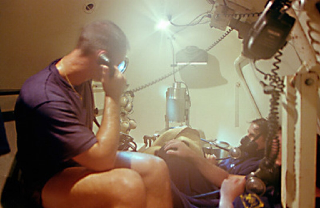 On board the U.S. Navy's salvage rescue ship USS Grasp (ARS 51) on July 29, 1996, U.S. Navy divers recompress following their dive on the ill-fated TWA flight 800 crash site. Descending to the crash site 120 feet below, divers recompress in a special chamber on board the Grasp to expel nitrogen in their blood stream. This process allows the divers to maximize their time on the ocean floor, by reducing the time needed to ascend between dives. 