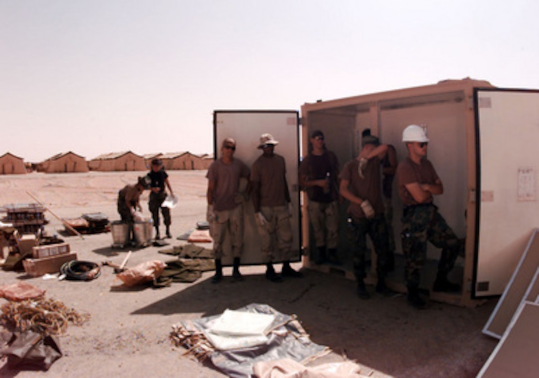 Engineers take a break in the shade of a shipping container at Prince Sultan Air Base at Al Kharj, Saudi Arabia, on August 9, 1996. U.S. Air Force engineers are erecting 500 tents to house U.S. personnel conducting Operation Southern Watch. Nearly 4,000 personnel, aircraft, and equipment are being moved from bases in Dhahran and Riyadh to the remote desert air base to reduce their vulnerability to terrorist attack. Southern Watch is the U.S. and coalition enforcement of the no-fly-zone over Southern Iraq. The engineers are from the 823rd Red Horse Squadron, Hurlburt Field, Fla., and the 49th Material Maintenance Group, Holloman Air Force Base, N. M. 