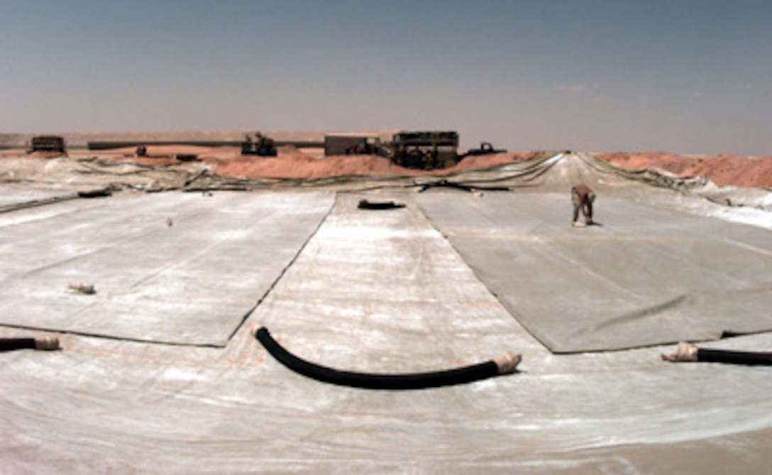 A U.S. Air Force airman checks an empty fuel bladder rolled out in the desert at Prince Sultan Air Base at Al Kharj, Saudi Arabia, on August 10, 1996. The bladder, capable of holding 5,000 gallons of jet fuel, is part of the fuel storage facility beginning to take shape at the base to support the relocation of U.S. personnel conducting Operation Southern Watch. Personnel, aircraft, and equipment are being moved from bases in Dhahran and Riyadh to the remote desert air base to reduce their vulnerability to terrorist attack. Southern Watch is the U.S. and coalition enforcement of the no-fly-zone over Southern Iraq. 