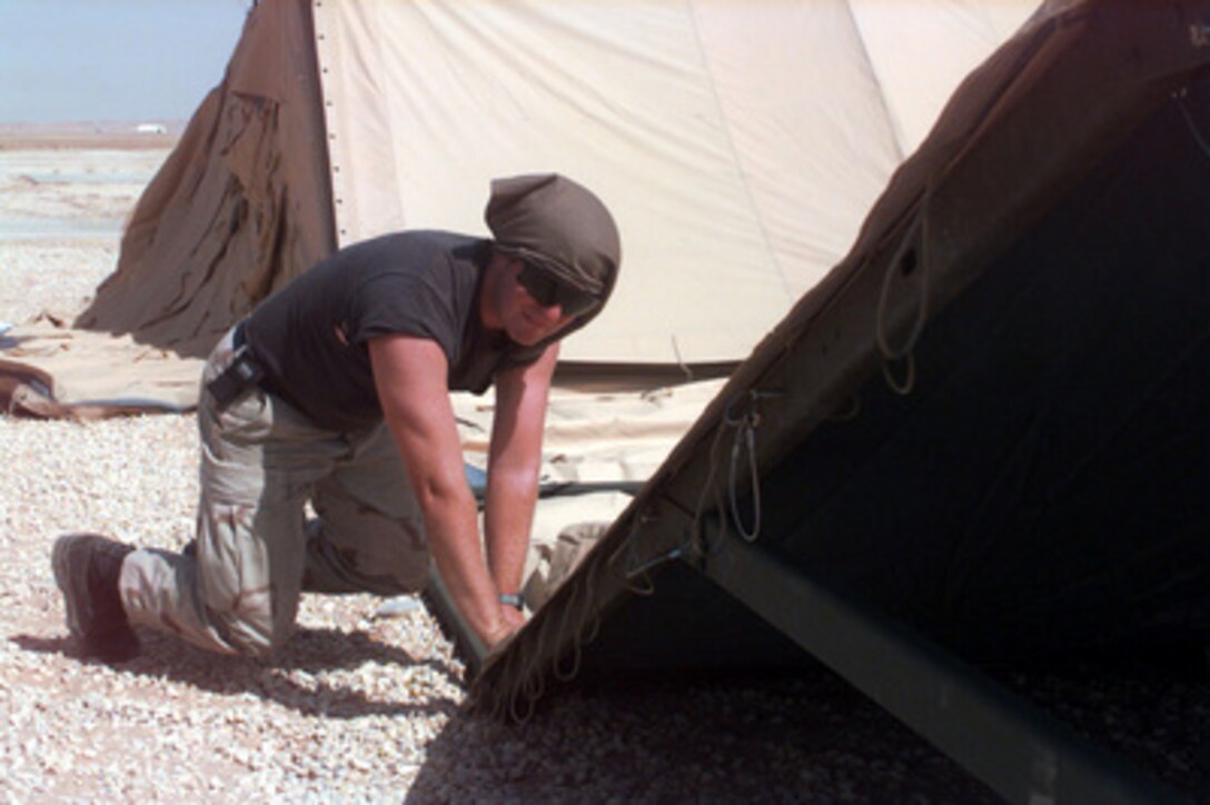Staff Sgt. Kevin Collins fastens the fabric to the frame of a tent being erected at Prince Sultan Air Base at Al Kharj, Saudi Arabia, on August 9, 1996. The tent is one of 500 tents U.S. Air Force engineers will put up to house U.S. personnel conducting Operation Southern Watch. Nearly 4,000 personnel, aircraft, and equipment are being moved from bases in Dhahran and Riyadh to the remote desert air base to reduce their vulnerability to terrorist attack. Southern Watch is the U.S. and coalition enforcement of the no-fly-zone over Southern Iraq. Collins is a Structure Specialist with the 823rd Red Horse Squadron, Hurlburt Field, Fla. 