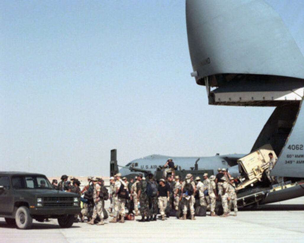 U.S. Air Force support personnel and equipment are off-loaded from a C-5B Galaxy while a C-141 Starlifter waits in the background at Prince Sultan Air Base at Al Kharj, Saudi Arabia, on Aug. 8, 1996. The aircraft are bringing in engineers, support personnel, equipment and supplies to construct a tent city to house U.S. personnel conducting Operation Southern Watch. Nearly 4,000 personnel, aircraft, and equipment are being moved from bases in Dhahran and Riyadh to the remote desert air base to reduce their vulnerability to terrorist attack. Southern Watch is the U.S. and coalition enforcement of the no-fly-zone over Southern Iraq. 