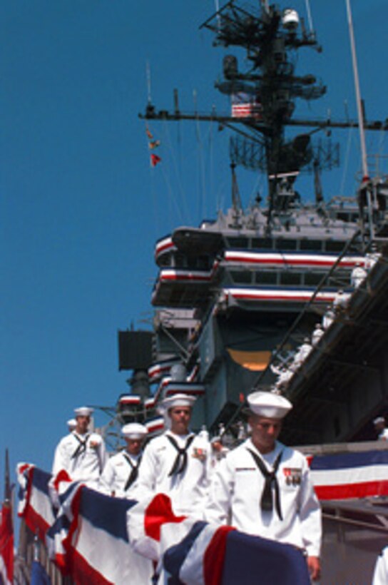 The crew of the aircraft carrier USS America (CV 66) marches down the gangway for the last time as their ship is decommissioned in ceremonies at the Norfolk Naval Shipyard in Portsmouth, Va., on August 9, 1996. America returned from its last deployment Feb. 24, where its squadrons flew 250 combat missions over the skies of Bosnia and Herzegovina. The Nation's Flagship and crew also distinguished themselves during Operation Desert Storm. America is the only carrier to have launched strikes against Iraqi targets from both sides of the Arabian Peninsula: Red Sea and Persian Gulf. The aircraft carrier was commissioned Jan. 23, 1965, at Norfolk Naval Shipyard. During its second deployment, America assisted with the rescue and medical treatment of crew members from the technical research ship USS Liberty (AGTR 5) after it was attacked by Israeli torpedo boats and jet fighters, June 8, 1967. America also completed three deployments to "Station"off the coast of Vietnam, where it spent as many as 112 consecutive days on station. 