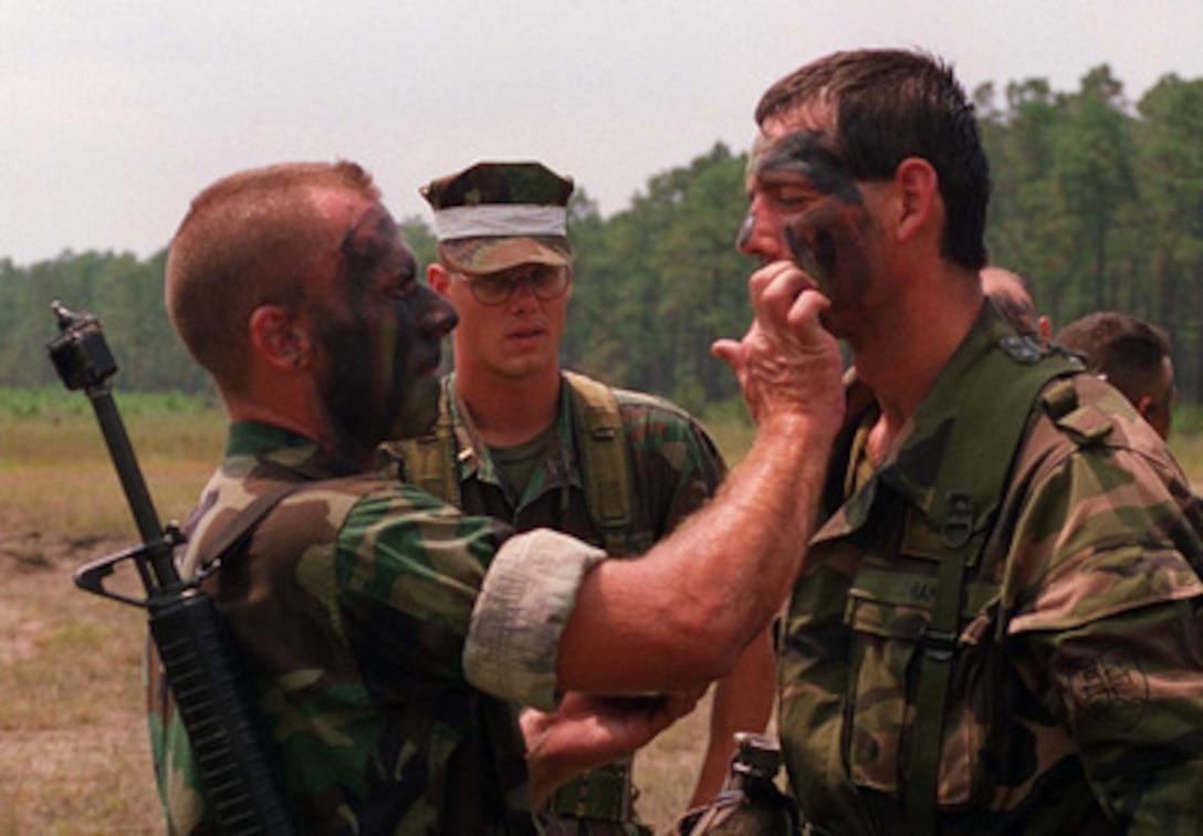 A U.S. Marine assists a Slovakian soldier in the application of his camouflage paint prior to a Situational Training Exercise at Camp Lejeune, N.C., on Aug. 19, 1996 as part of Cooperative Osprey '96. Cooperative Osprey '96 is a NATO sponsored exercise as part of the alliance's Partnership for Peace program. The aim of the exercise is to develop interoperability among the participating forces through practice in combined peacekeeping and humanitarian operations. Three NATO countries and 16 Partnership for Peace nations are taking part in the field training exercise. 