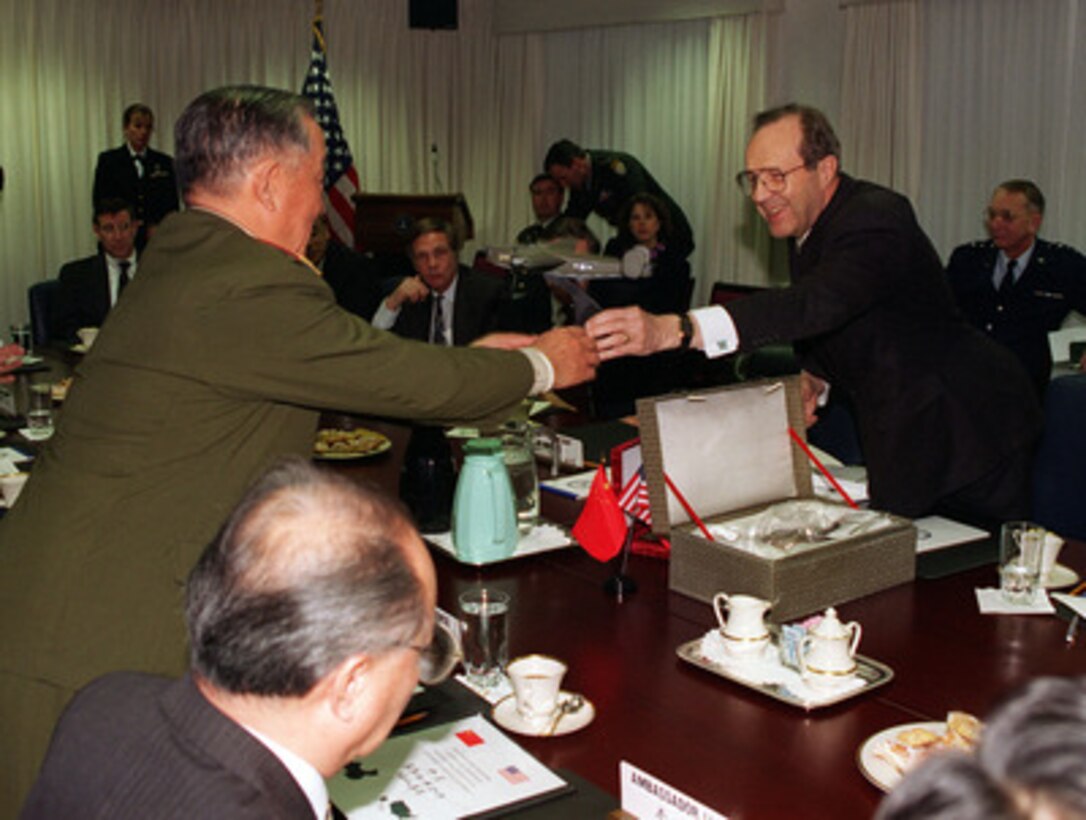 Secretary of Defense William J. Perry (right) presents a model of a B-24 Liberator bomber to People's Republic of China Gen. Chi Haotian (left) prior to a meeting between the two defense ministers in the Pentagon on Dec. 9, 1996. Gen. Chi had earlier presented Perry with personal effects from the 1944 crash of a B-24 Liberator bomber in China. The bomber was flying a supply mission over the Himalayas. The U.S. intends to send a team of specialists to China to recover the remains of the crew. 