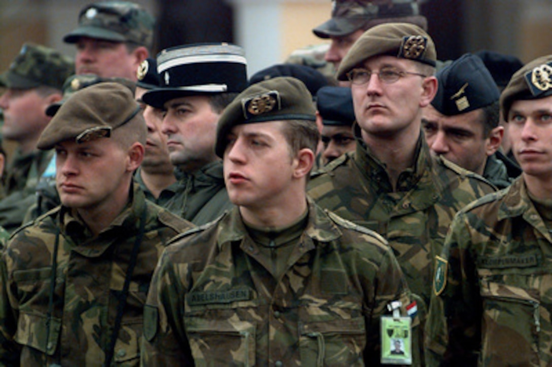 Members of the Dutch, French, German, and U.S. military watch as an Italian honor guard hoists the new Stabilization Force flag during the Stabilization Force (SFOR) activation ceremony in Sarajevo, Bosnia and Herzegovina, on Dec. 20, 1996. The ceremony recognizes the transition from the Implementation Force (IFOR) and the change of mission from the implementation of the Dayton Peace Accords to SFOR and the stabilization of the changes brought about by that treaty. 