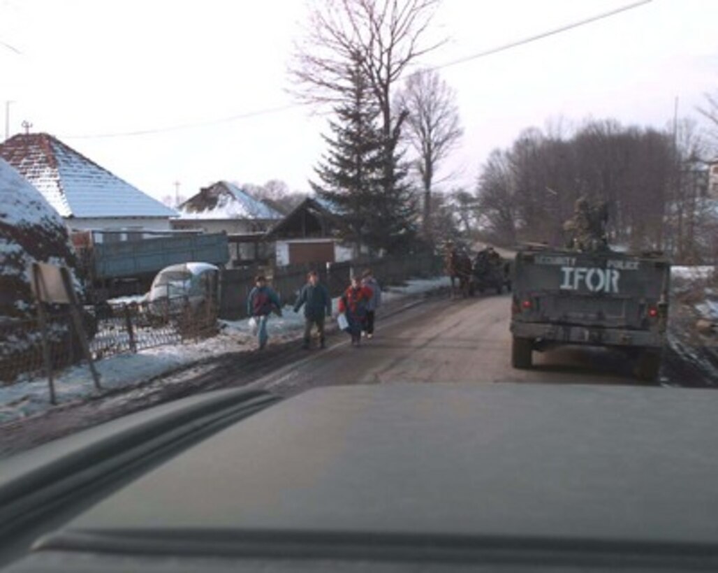 Local children watch as a convoy of U.S. Humvees passes by on their way to Tuzla, Bosnia and Herzegovina, on Jan. 23, 1996, during Operation Joint Endeavor. U.S. troops are deployed to Tuzla Air Base as part of the NATO Implementation Force (IFOR) in Bosnia and Herzegovina. 