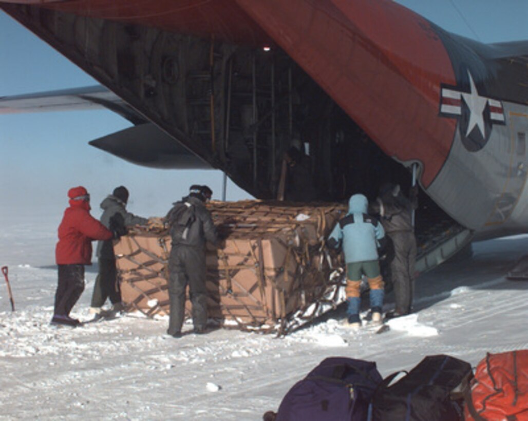 U.S. Navy pilots, loadmasters, and National Science Foundation scientists struggle together against fierce, biting Antarctic winds during a research camp pull-out mission atop the Grosvenor Mountain Range on Jan. 22, 1996. The National Science Foundation, U.S. Navy, Air Force, Coast Guard and Army work together to support scientific research year round. 