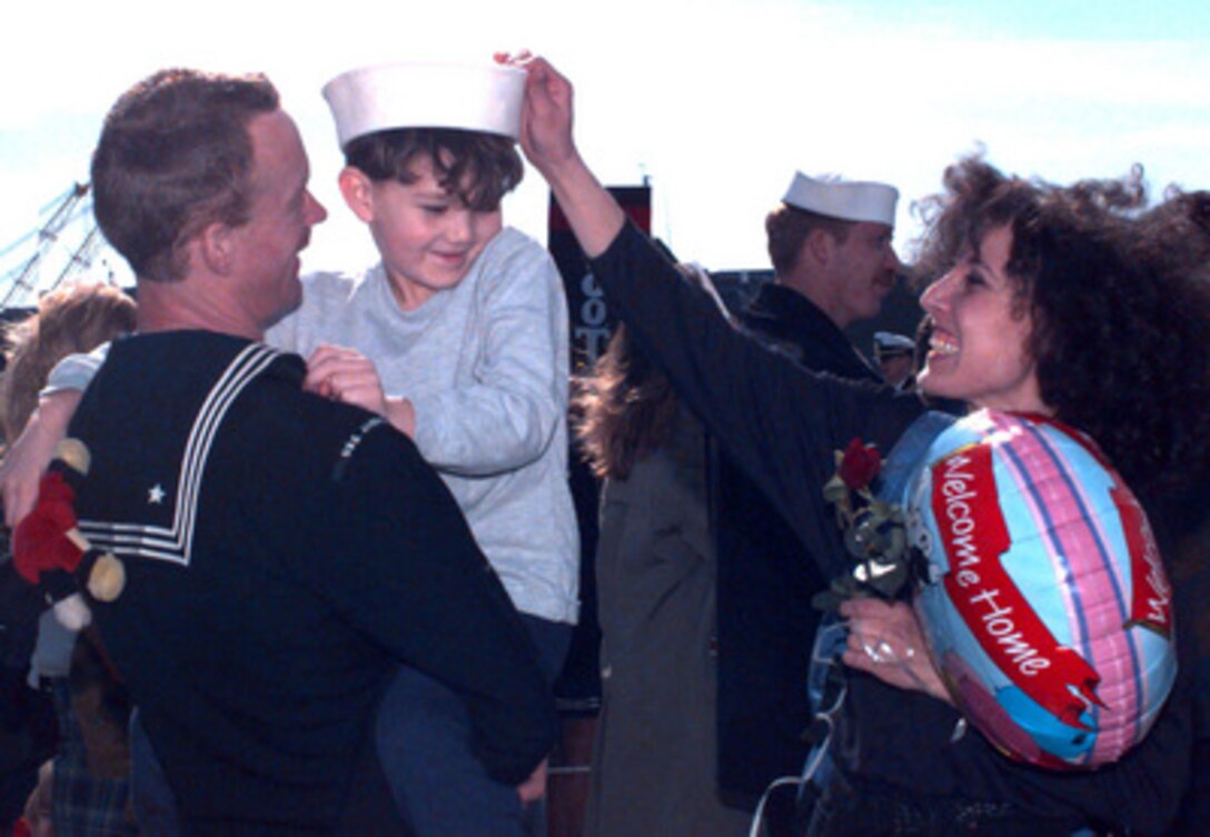 Petty Officer 2nd Class John Neet, U.S. Navy, holds his son Dustin while his wife Cafada Neet places her husband's hat on her son's head on Jan. 24, 1996. The family was re-united in Norfolk, Va., when Petty Officer Neet's ship the aircraft carrier USS America (CV 66) returned from a six month, Mediterranean Sea deployment. Additionally, the America Battle Group operated in the Adriatic Sea in support of the NATO Implementation Force (IFOR) in Bosnia and Herzegovina for Operation Joint Endeavor. This was the last deployment for the USS America which is scheduled for decommissioning later this year. Neet, from Alameda, Calif., is an Aviation Boatswain's Mate (Fuels) onboard the ship. 
