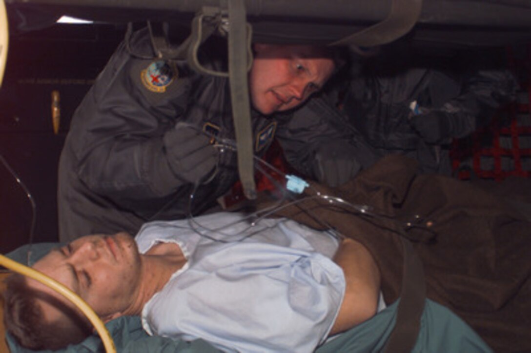 U.S. Air Force Capt. Brad Shirra checks the IV of U.S. Army Spc. Martin Begosh during his medical evacuation flight from Taszar, Hungary to Ramstein Air Base, Germany, on Jan. 3, 1996. Begosh was wounded Dec. 30 when the Humvee he was driving on patrol struck a land mine in northern Bosnia and Herzegovina. Begosh is a military policeman with the 709th Military Police Battalion, Hanau Army Post, Germany. Shirra is attached to the U.S. Air Force 86th Aeromedical Evacuation Squadron at Ramstein Air Base, Germany. Begosh is the first soldier wounded in the NATO Operation Joint Endeavor. 