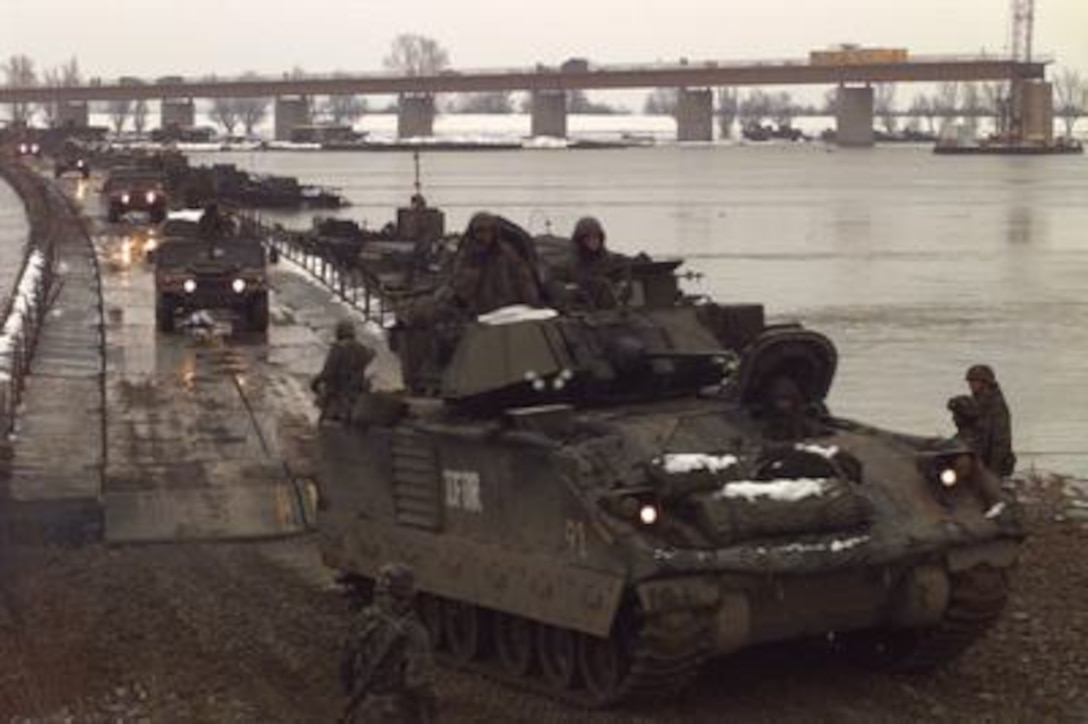 A U.S. Army Bradley Fighting Vehicle leads a column of Humvees across the U.S. Army pontoon bridge over the Sava River from Zupania, Croatia, into Bosnia and Herzegovina on Dec. 31, 1995. The bridge has become one of the primary routes for the NATO Implementation Force (IFOR) deployment into Bosnia and Herzegovina for Operation Joint Endeavor. 